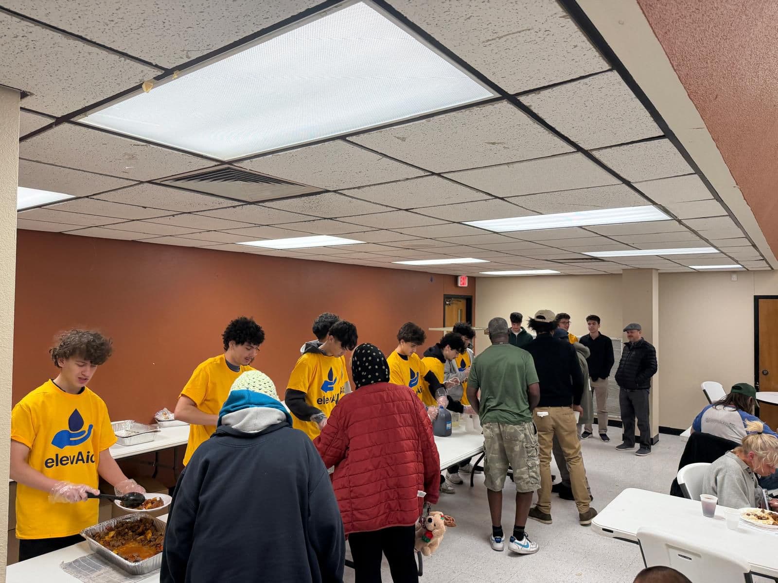 Elevaid and GLOWS volunteers distributing food to homeless individuals at Salvation Army Gym in Garland